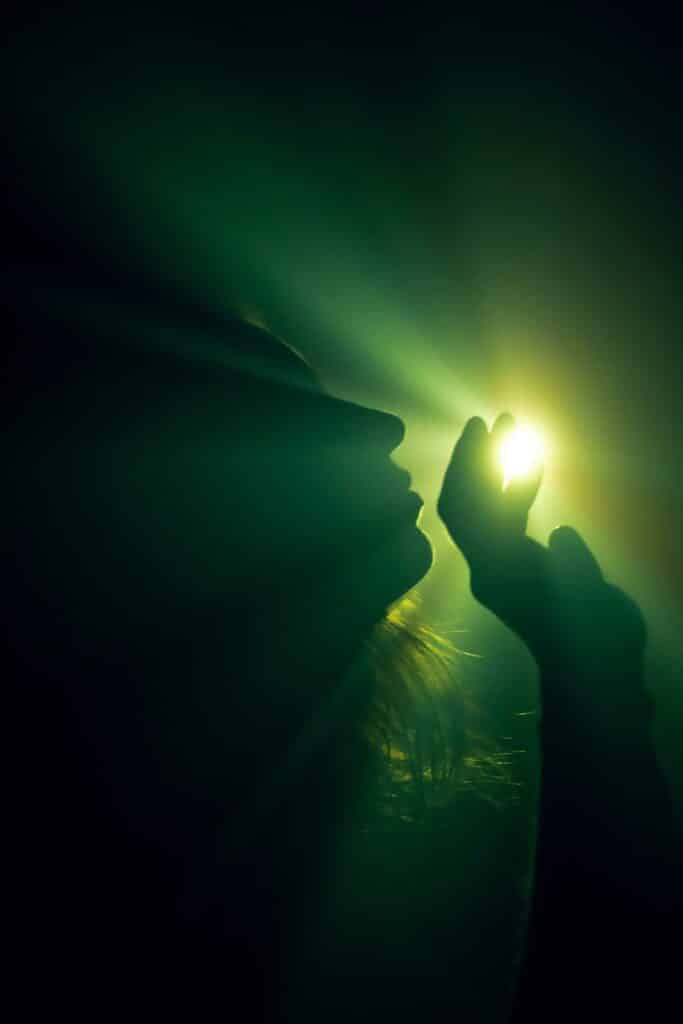 A silhouette of a person reaching for a mystical light source, creating an ethereal ambiance.