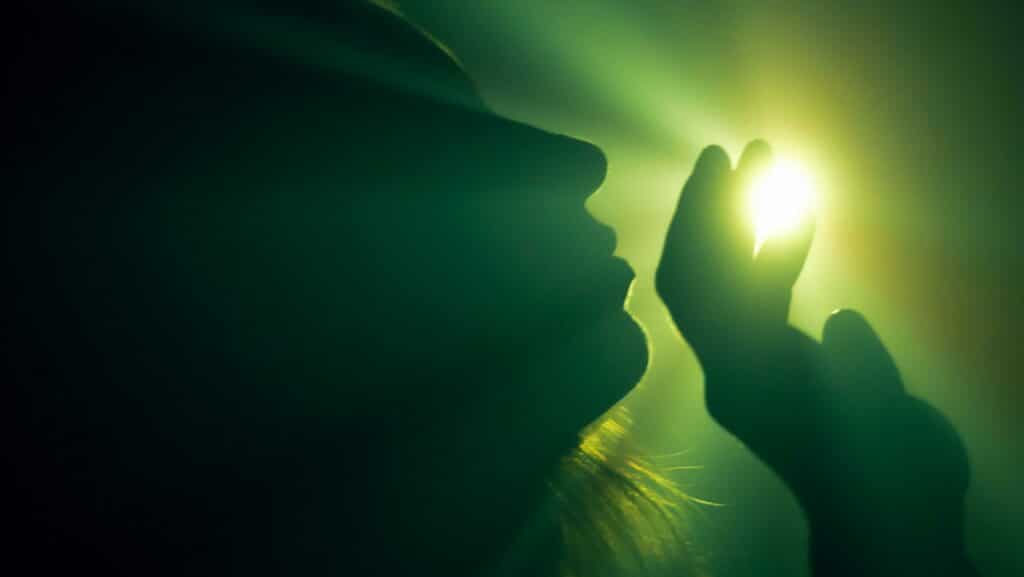 A silhouette of a person reaching for a mystical light source, creating an ethereal ambiance.